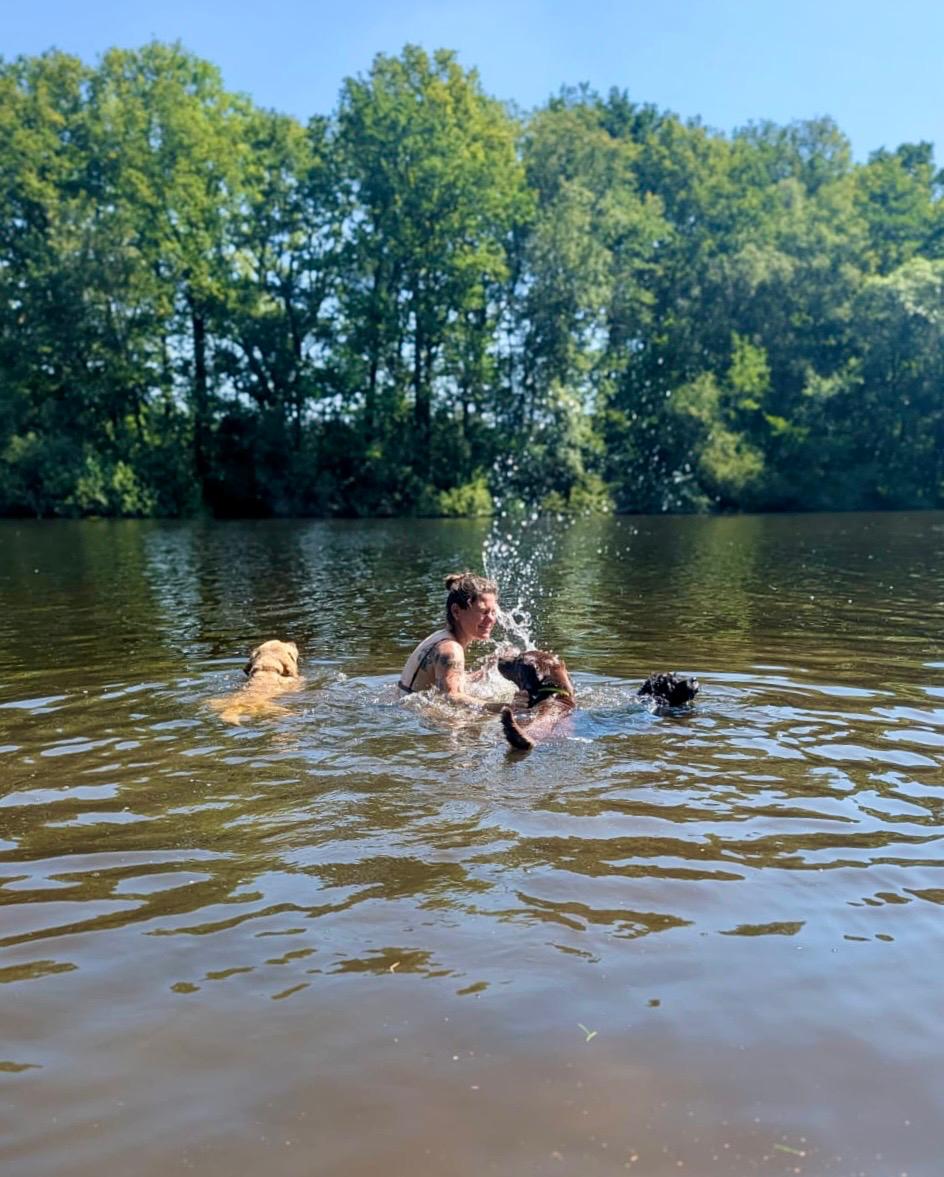 Anneke schwimmt mit mehreren Hunden in einem See